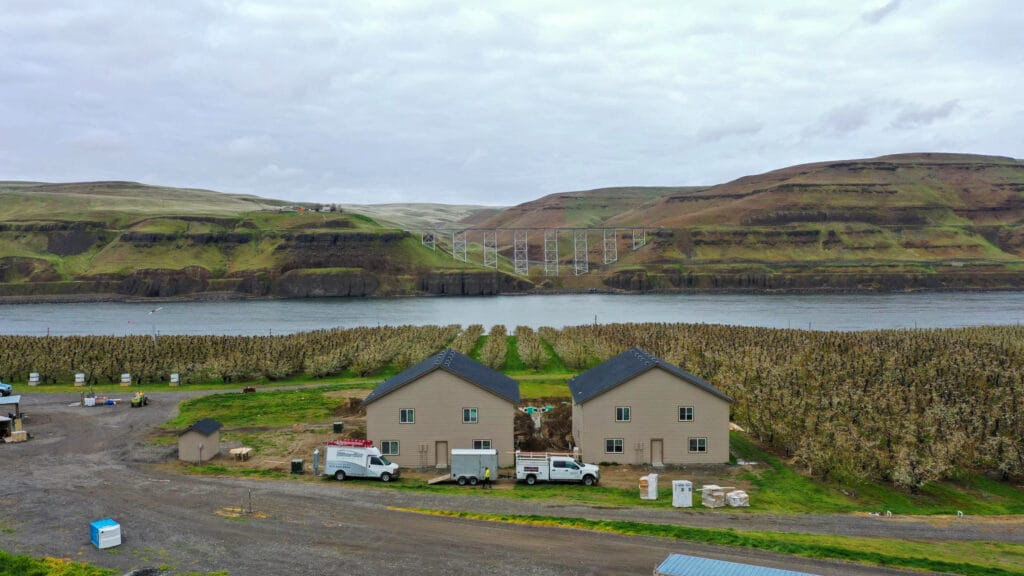 Riverside landscape with buildings and orchards.