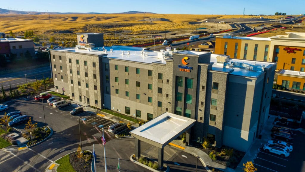 Hotel with parking lot and surrounding landscape view.