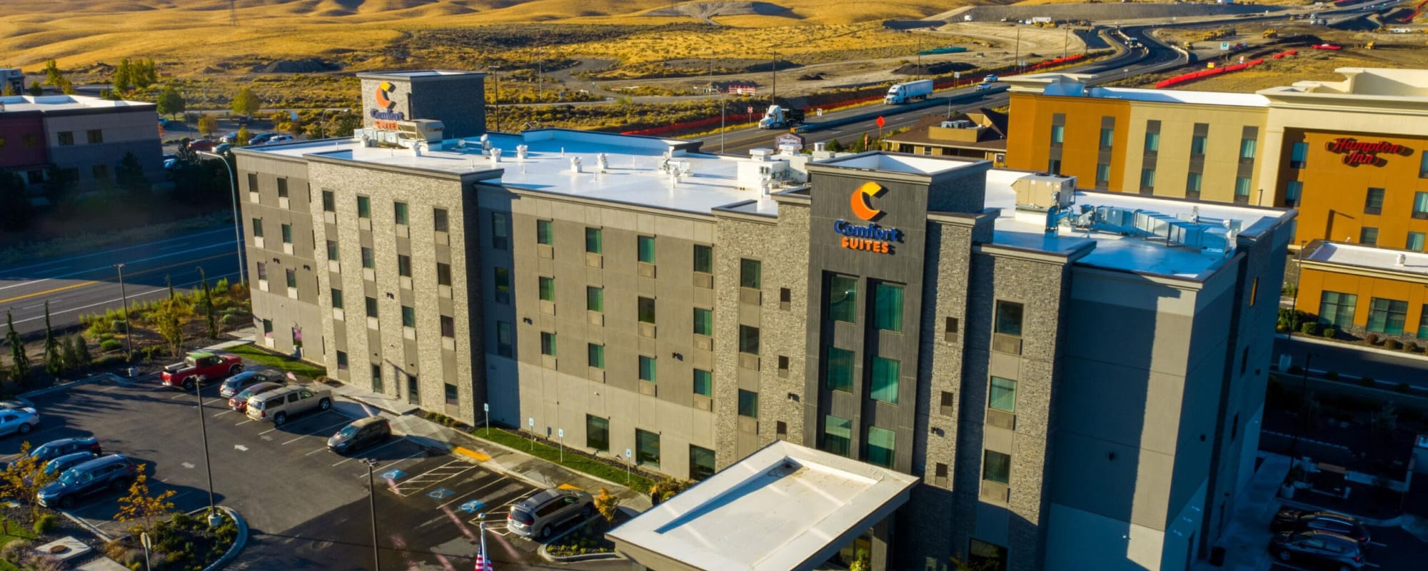 Aerial view of modern hotel building and parking area.