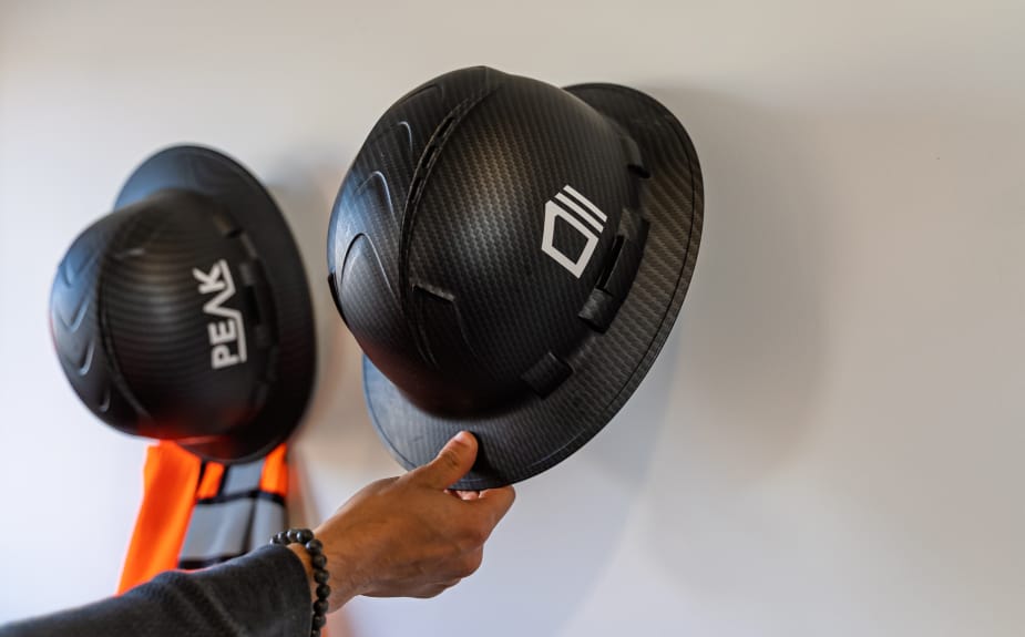 commercial Hand holding black hard hat on wall