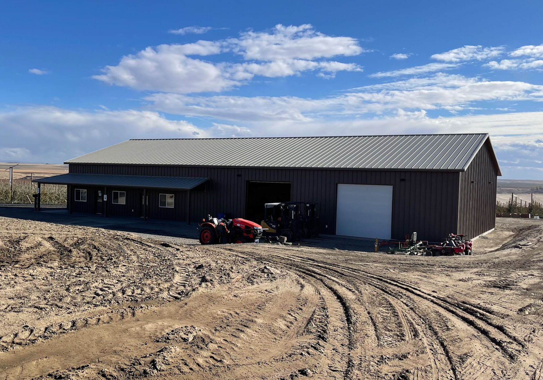 Large barn with tractor on muddy ground