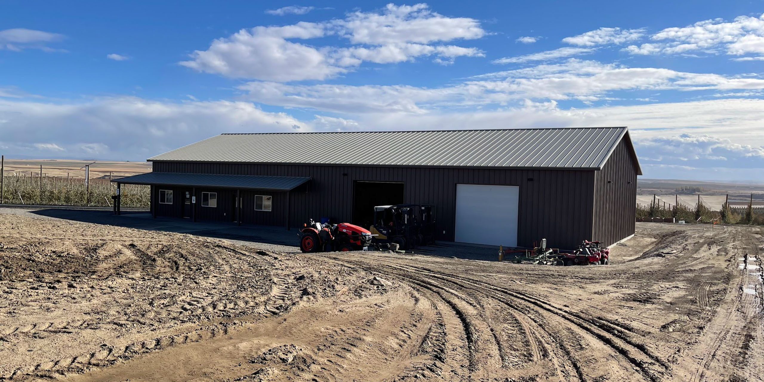 Large barn with tractor on muddy ground