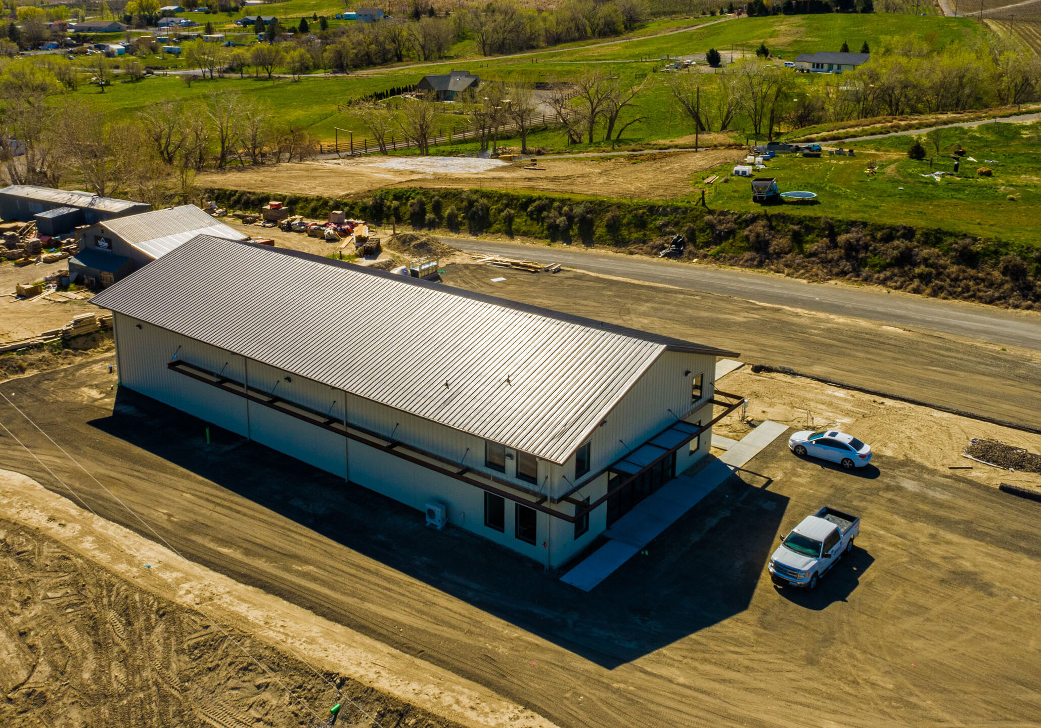 Aerial view of rural warehouse surrounded by greenery.