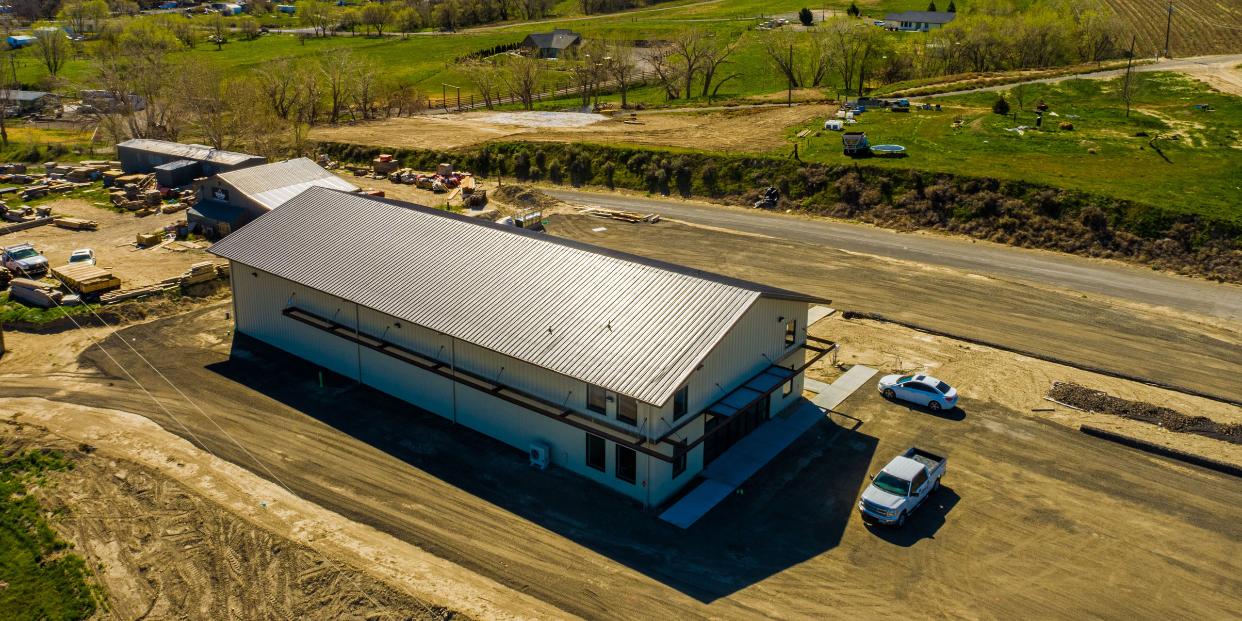 Aerial view of rural warehouse surrounded by greenery.