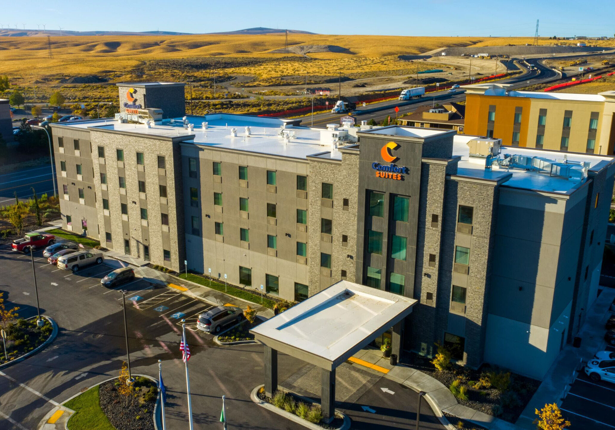 Hotel with parking lot and surrounding landscape view.