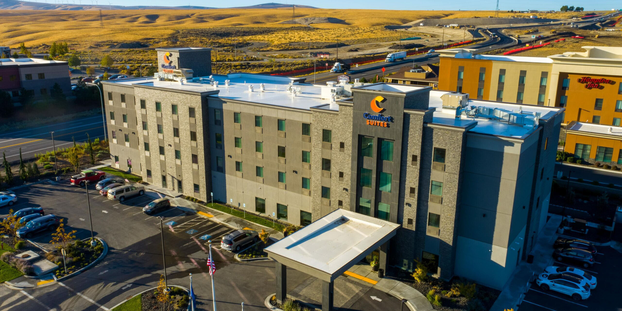 Hotel with parking lot and surrounding landscape view.