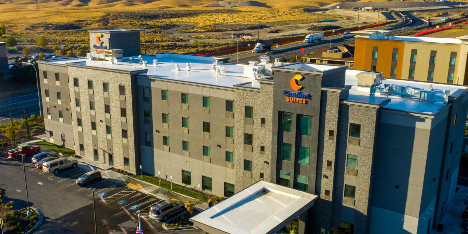 Aerial view of modern hotel building and parking area.